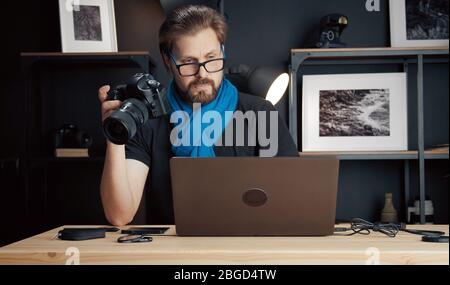 Photographer holding camera looking laptop Stock Photo