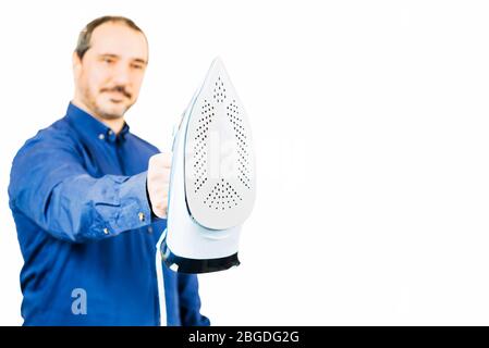 man in a blue shirt holding an iron on white background Stock Photo