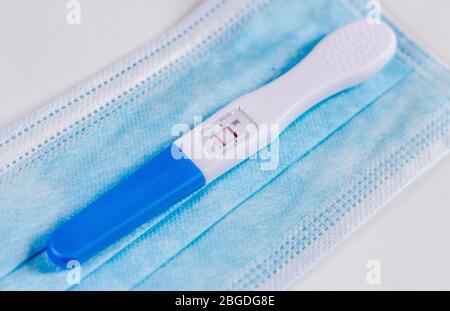 Positive pregnancy test on a face mask. Expecting during pandemic. Healthy pregnancy. Stock Photo