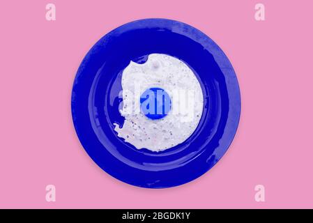 Blue fried egg in a colored plate on a pink background. Contemporary art, collage Stock Photo