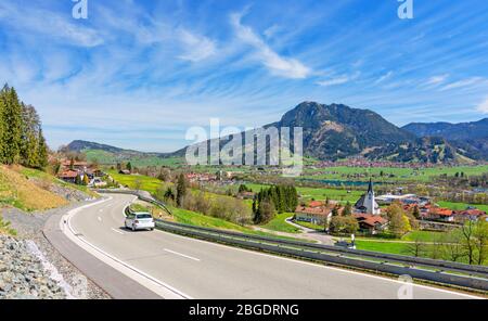 Country road in the Allgäu region in spring. Landscape with villages, forest and Grünten mountain in the centre. Bavaria, Germany Stock Photo