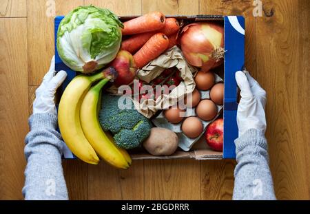 Female wearing gloves holding market box delivery Stock Photo