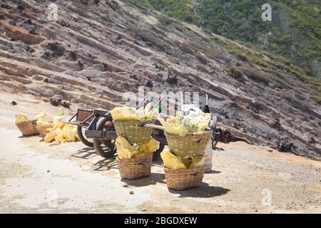 Sulfur carriers basket at Kawah Ijen, Indonesia. Heavy basket laden by pieces of natural sulfur to carry by miners from crater mine. Manual labour intensive sulphur mining operation in Kawah Ijen volcano. Stock Photo