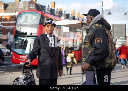 Two men standing on Brixton Road with a bus in the background, London Stock Photo