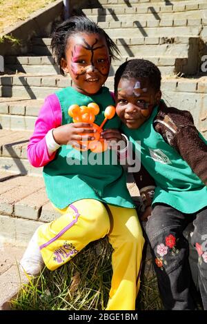 Soweto, South Africa - July 18, 2012: Young African Preschool children playing with animal balloons on the playground Stock Photo
