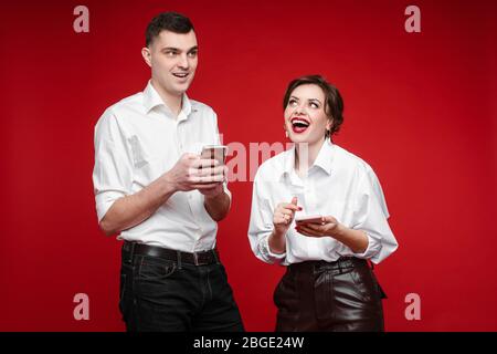 Happy young couple with gadgets standing in studio Stock Photo