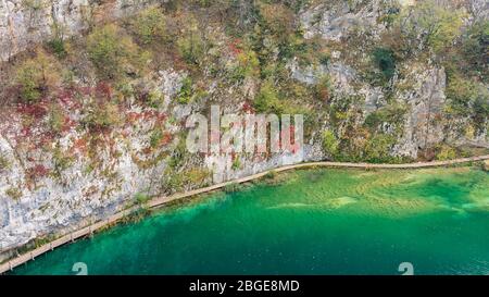 A wooden footbridge running along one of the multiple lakes of the Plitvice Lakes National Park with beautiful autumn colors, Croatia Stock Photo