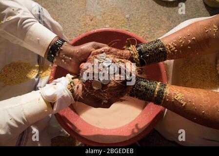 Closeup pf an Indian Hindu wedding couple holding a coconut and coins in their hands during a ritual Stock Photo