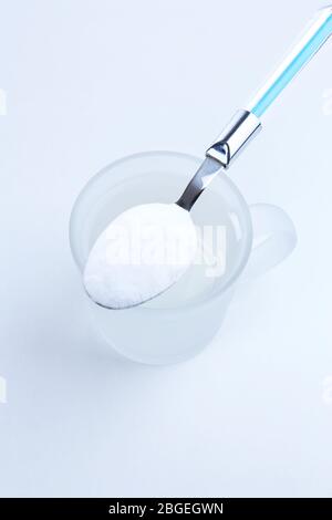 Spoon of baking soda over glass of water, isolated on white Stock Photo