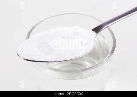 Spoon of baking soda over glass of water, isolated on white Stock Photo