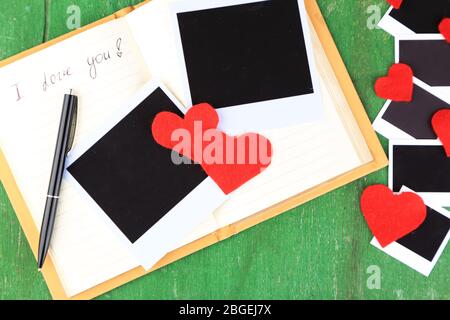 Blank old photos and decorative hearts on old notebook, on color wooden background Stock Photo