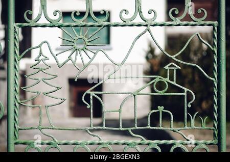 house and landscape shaped gate door on an old iron fence in a mountain village Stock Photo