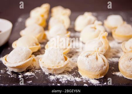 Homemade uncooked russian pelmeni meat dumplings italian ravioli on cutting board Stock Photo