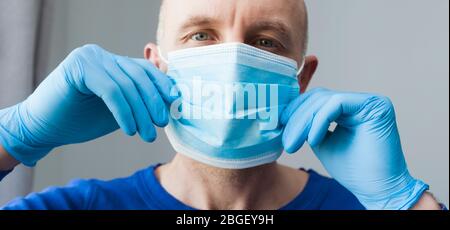 Confident young surgeon doctor in latex protective gloves wearing medical mask on face. Man professional medic in medical gloves put on protective