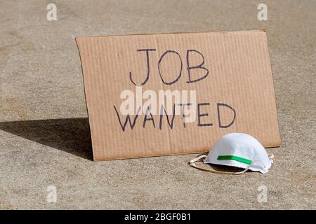 Job wanted cardboard sign and N94 respirator mask. Concept of recession, unemployment, job layoffs due to Covid-19 coronavirus pandemic Stock Photo