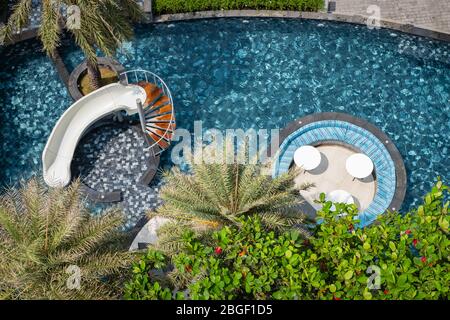 CHON BURI, THAILAND - FEBRUARY 16, 2019: Top view of tropical swimming pool, water slide, seats and table in the pool at the resort, hotel on Pattaya Stock Photo