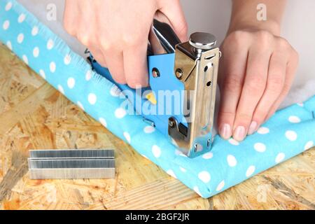Fastening fabric and board using construction stapler Stock Photo