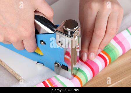 Fastening fabric and board using construction stapler Stock Photo