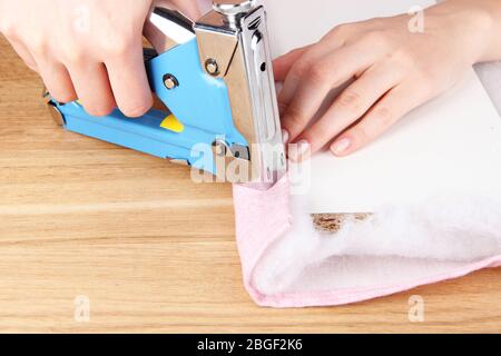 Fastening fabric and board using construction stapler Stock Photo
