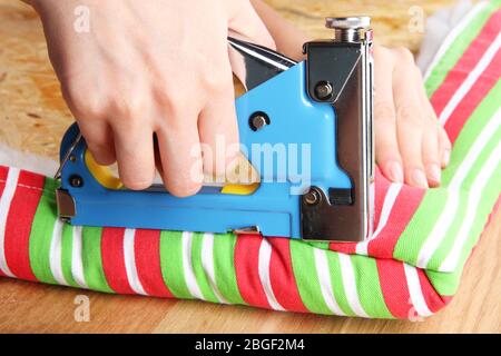 Fastening fabric and board using construction stapler Stock Photo