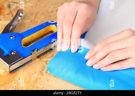 Fastening fabric and board using construction stapler Stock Photo
