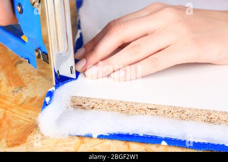 Fastening fabric and board using construction stapler Stock Photo