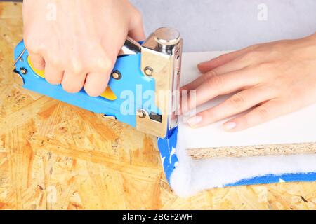 Fastening fabric and board using construction stapler Stock Photo