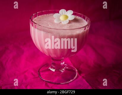 Pink strawberry angel delight in a glass bowl with pink table cloth and daisy decoration. Towcester, England Stock Photo