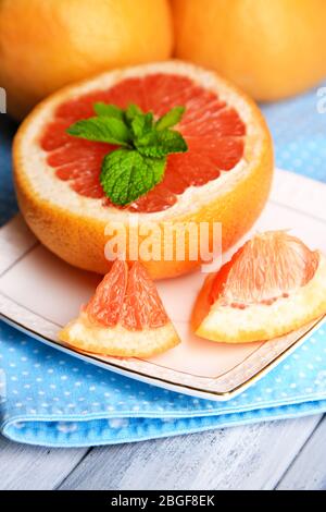 Ripe grapefruits on plate on color wooden background Stock Photo