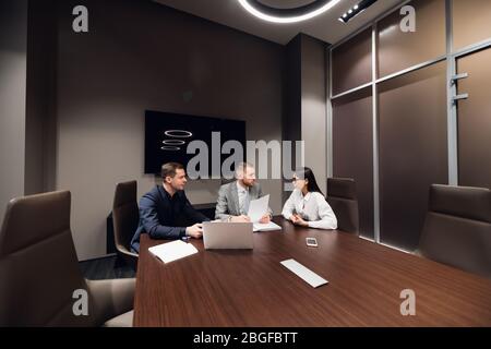 Portrait of three co-workers discussing business plan in office Stock Photo