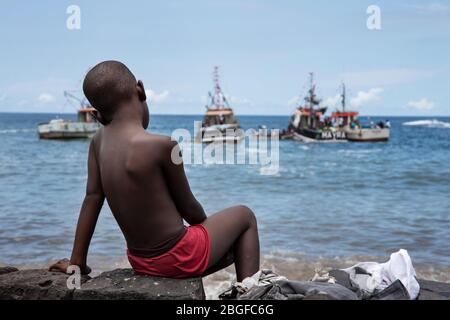 boy watching boats at the fishermen's party in Cidade Velha, Cape Verde Stock Photo
