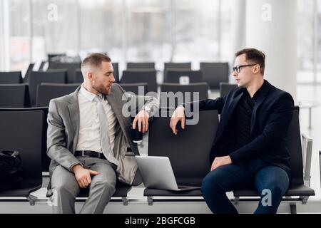 Business colleagues waiting at airport lounge standing and talking Stock Photo