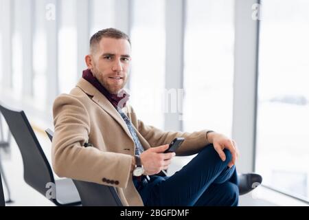 young busy man waiting for departure at the airport while using his phone Stock Photo