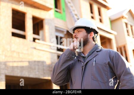 Portrait of thinking foreman wearing hardhat on constuction site. Stock Photo