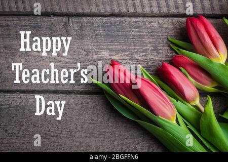 Happy Teacher's Day Card Concept. Spring tulips flowers on a old wooden background. Top view, flat lay Stock Photo