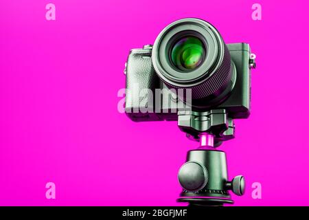 Professional camera on a tripod, on a pink background. Record videos and photos for your blog or report. Free space, isolated. Stock Photo