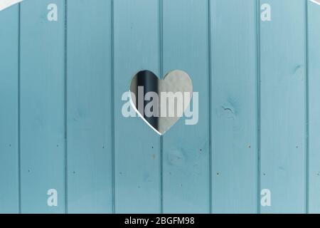 a close up view of a wooden door that has a small heart shape cut out of the middle Stock Photo