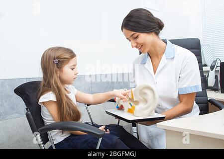 Pediatrician and girl patient look at the camera after consultation with an otolaryngologist. Girls have no hearing problems Stock Photo