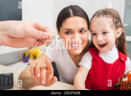 Child is not afraid that she needs to use a hearing aid on her ear. Mother of child is very pleased that her daughter will hear the world. Deafness tr Stock Photo