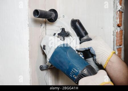 Builder man cutting electrical chase in concrete wall with groove machine diamond crown Stock Photo