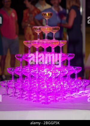 pink light in champagne glasses standing in a tower filled party close up Stock Photo