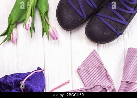 Stylish shoes, clothes and spring flowers tulips on a white wooden background. Flat lay shot of girls spring clothing Stock Photo