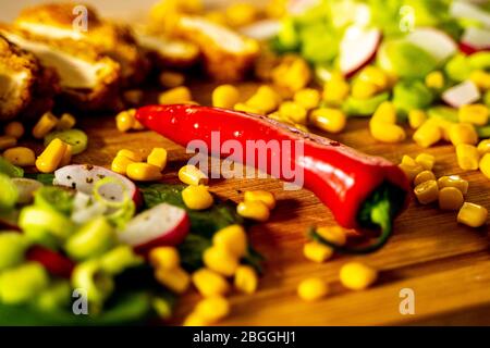 Cooking ingredients on wooden surface with red pepper and corn Stock Photo