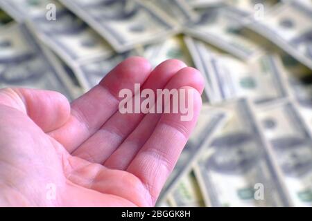 The begging hand on the background of dollar bills. An empty hand represents poverty. Those in need are asking for help. Crisis, the concept of impove Stock Photo