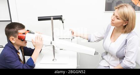 Pleoptics is a treatment for amblyopia. Woman optometrist monitors boy's visual acuity Stock Photo