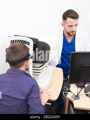 doctor examines a boy's cornea using a special ophthalmic apparatus. Glaucoma treatment Stock Photo