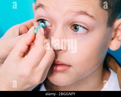 Optometrist trying on a contact lens to a teenage boy. Contact lenses for vision correction in children. Contact lens close up Stock Photo