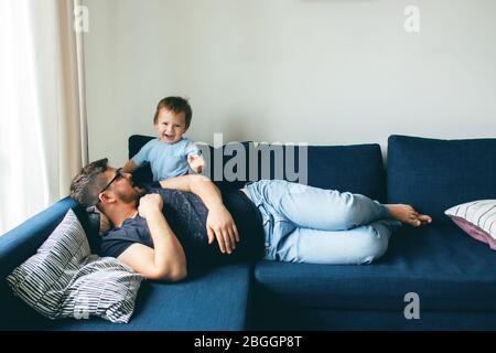 Dad is playing with his son. The baby is laughing. The concept of communication between dads and children, entertainment in quarantine, stay at home. Stock Photo