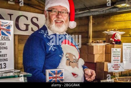 Bearded, smiling stall holder dressed as Father Christmas, selling Christmas puddings at the Waddesdon  Manor Food Fair - 2016 Stock Photo