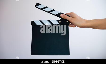Close up female hold in hand wooden black clapperboard isolated on gray background. Cinematography production concept. Copy space advertising mock up. Stock Photo